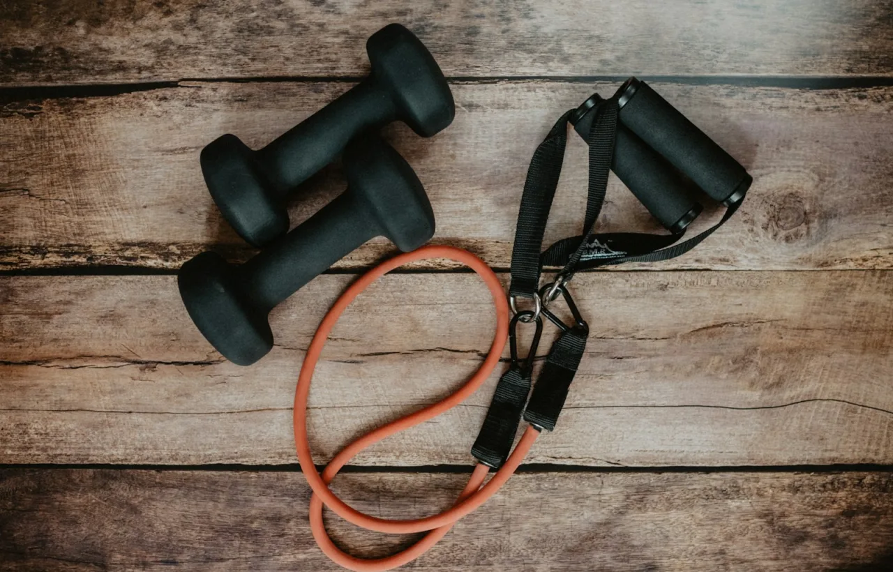 Dumbbells and a resistance band on a wooden floor