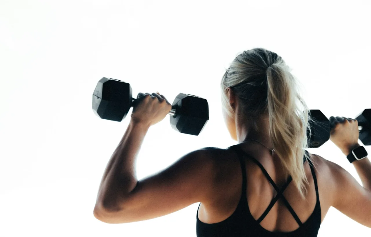 Woman doing a dumbbell shoulder press, seen from behind