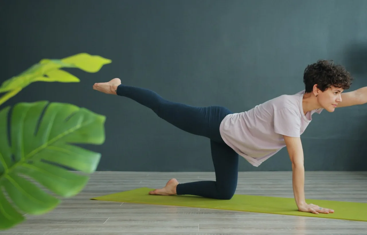 Woman doing a bird-dog exercise on a mat at home