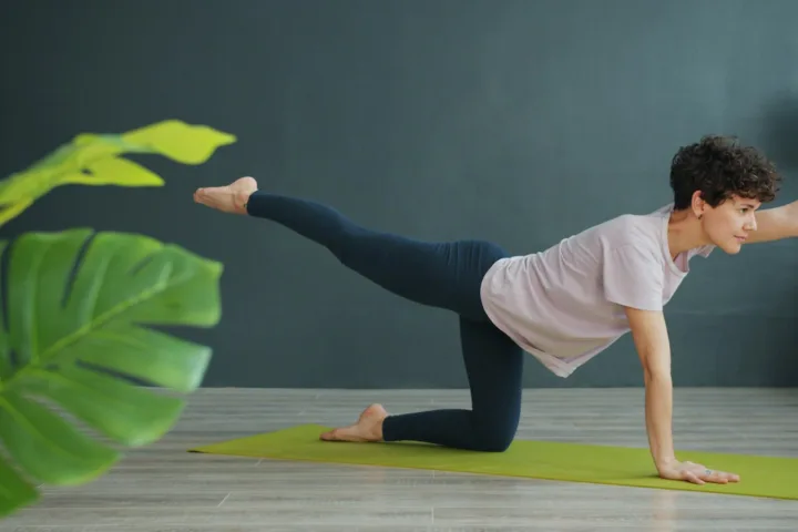 Woman doing a bird-dog exercise on a mat at home