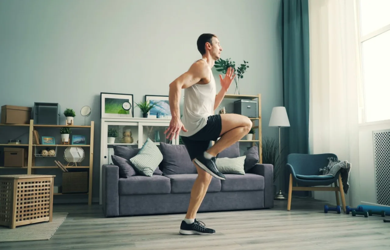 Man doing high knees in a living room for a no-equipment cardio workout