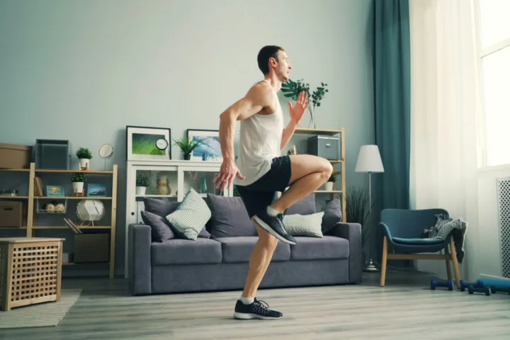 Man doing high knees in a living room for a no-equipment cardio workout