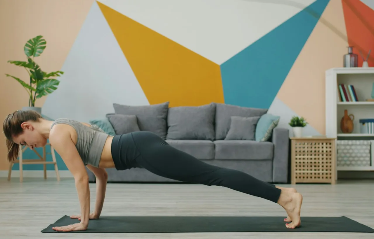 Woman holding a plank on a yoga mat in a living room