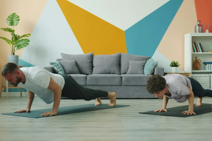 Man and woman doing push-ups on yoga mats at home