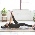 Woman lying on an exercise mat at home doing a leg raise
