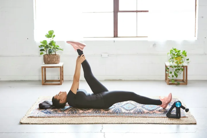 Woman lying on an exercise mat at home doing a leg raise